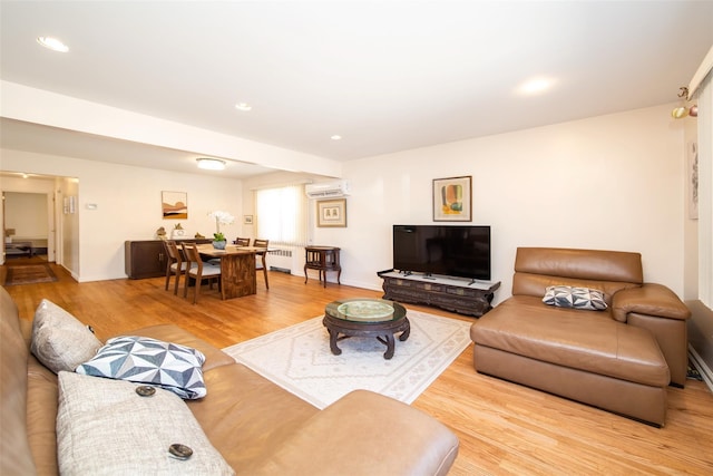 living room featuring radiator, light wood-style flooring, recessed lighting, and a wall mounted AC