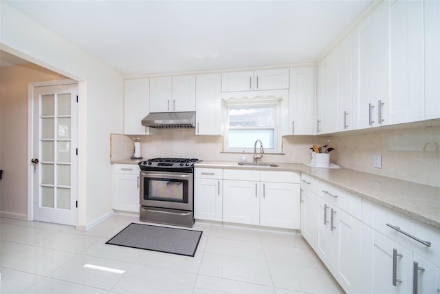 kitchen featuring under cabinet range hood, a sink, white cabinets, decorative backsplash, and gas range