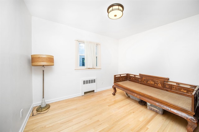 sitting room with light wood finished floors, radiator heating unit, and baseboards