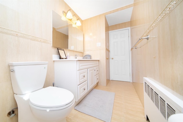 bathroom with double vanity, tile walls, toilet, and radiator