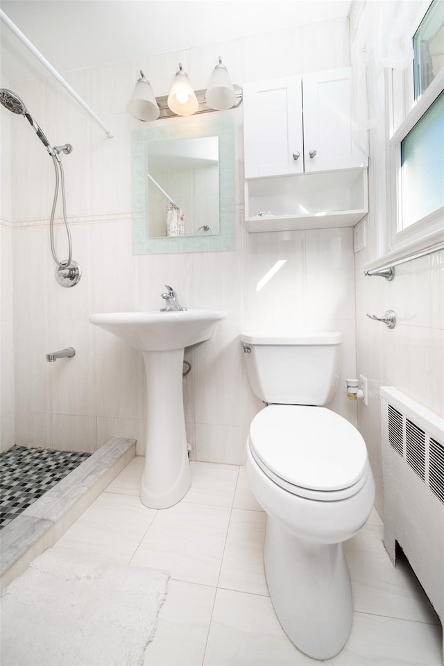 bathroom featuring tile walls, radiator, toilet, a shower stall, and a sink