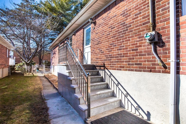 view of exterior entry featuring brick siding and fence