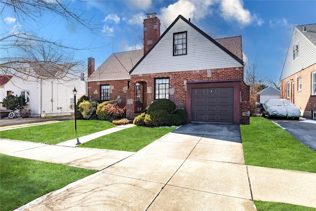 view of front facade featuring brick siding, a chimney, a shingled roof, a front yard, and driveway