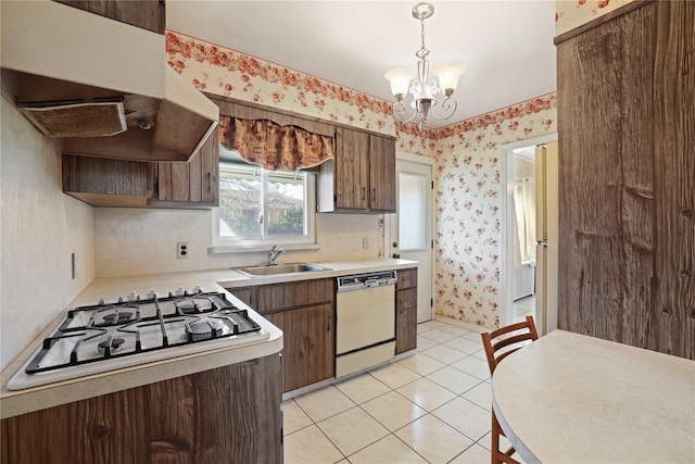 kitchen with a sink, wallpapered walls, white appliances, and light countertops