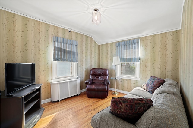 living room featuring radiator, ornamental molding, vaulted ceiling, wood finished floors, and baseboards