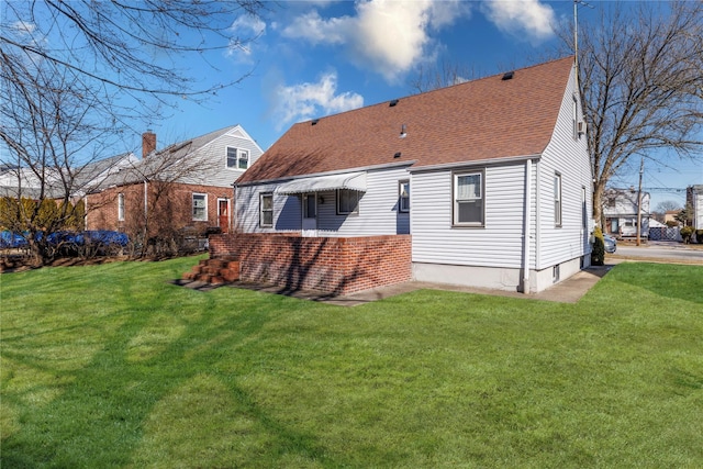 rear view of house with a shingled roof and a yard