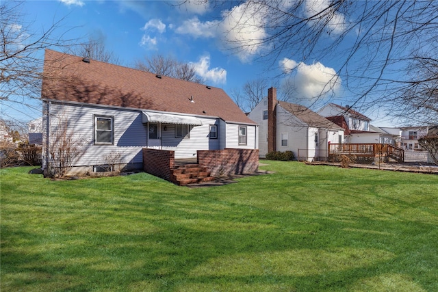 rear view of house with a shingled roof and a lawn