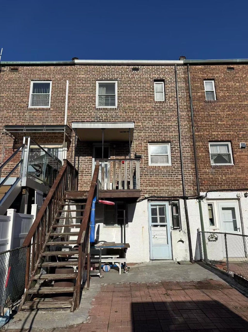 back of house featuring stairs, fence, and brick siding