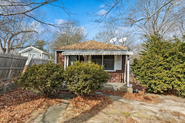 view of front of house with a porch, roof with shingles, and fence