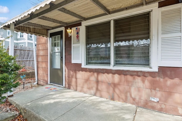 doorway to property with fence and a porch