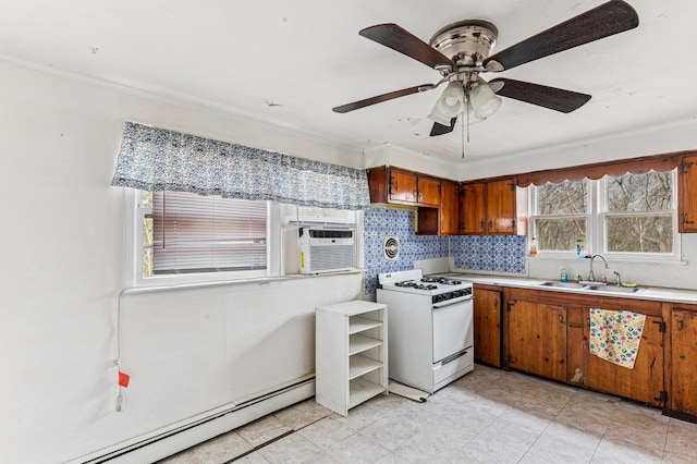 kitchen with white gas stove, a baseboard heating unit, a sink, light countertops, and brown cabinets