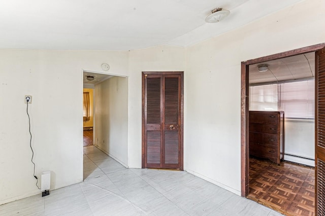 unfurnished bedroom with lofted ceiling, baseboards, and baseboard heating