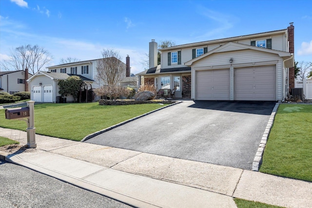 traditional home featuring brick siding, a chimney, a front yard, a garage, and driveway