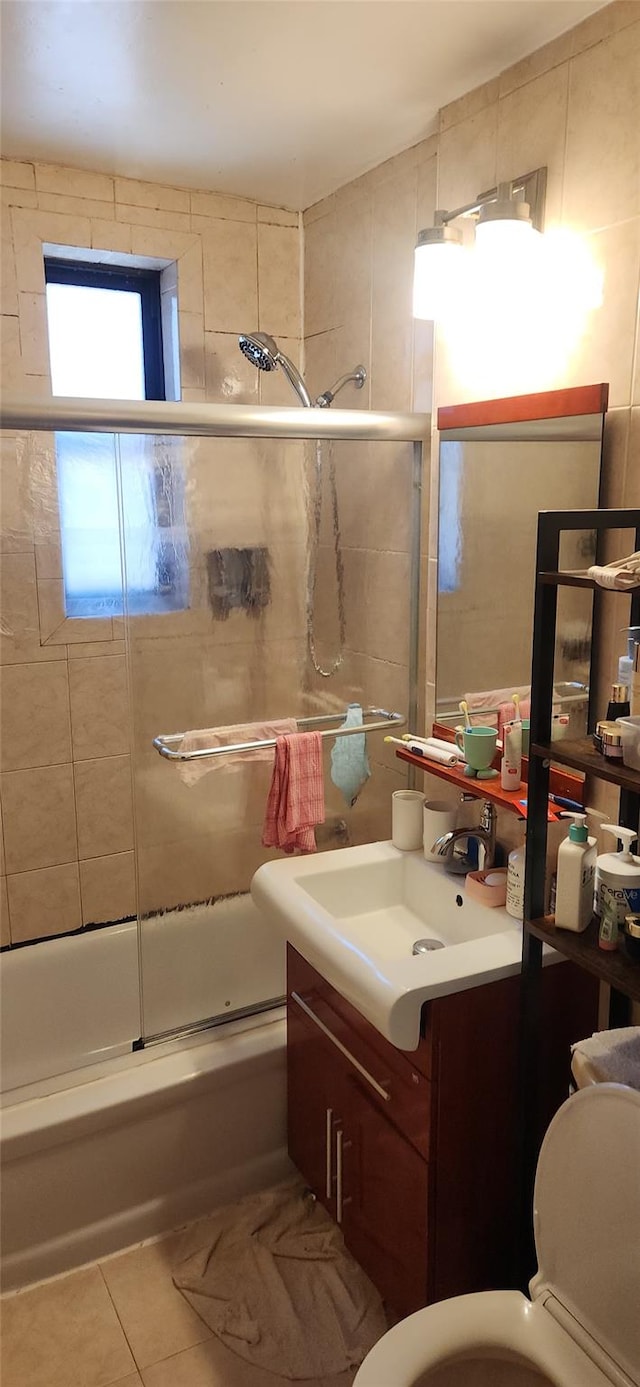 bathroom featuring toilet, bath / shower combo with glass door, vanity, and tile patterned floors