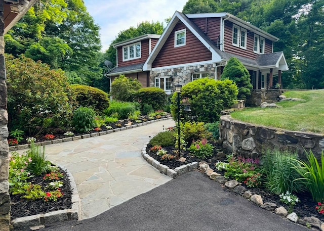 view of front of home featuring stone siding, log veneer siding, and a front yard