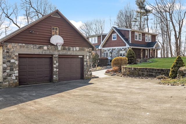 view of front of property with driveway, stone siding, and a garage