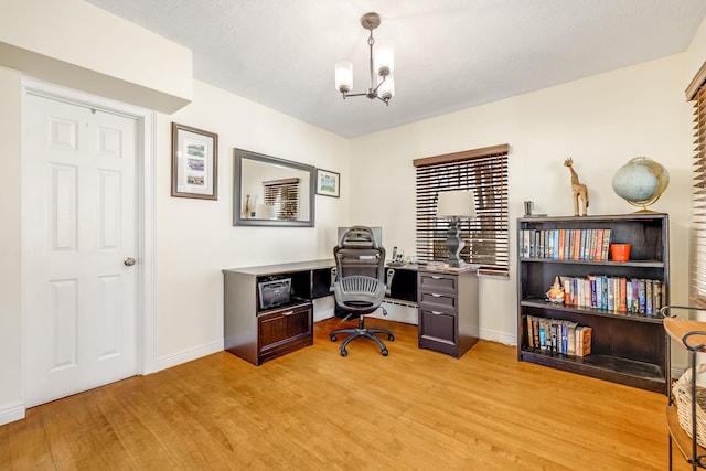 home office featuring baseboards, light wood-type flooring, and an inviting chandelier