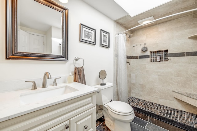 bathroom with toilet, tiled shower, vanity, and tile patterned floors