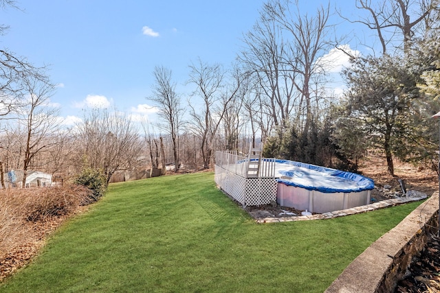 view of yard with a deck and a covered pool