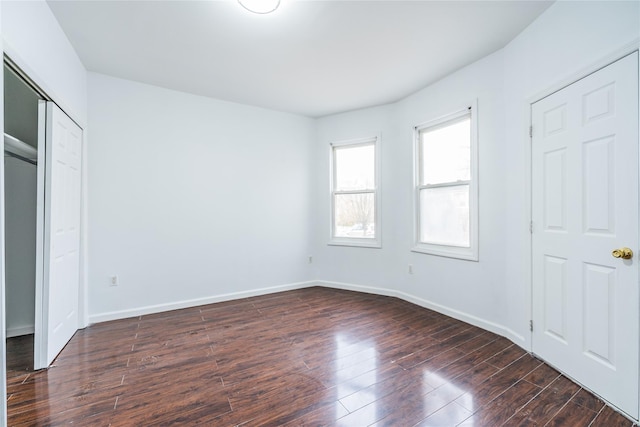 unfurnished bedroom with dark wood-style flooring and baseboards