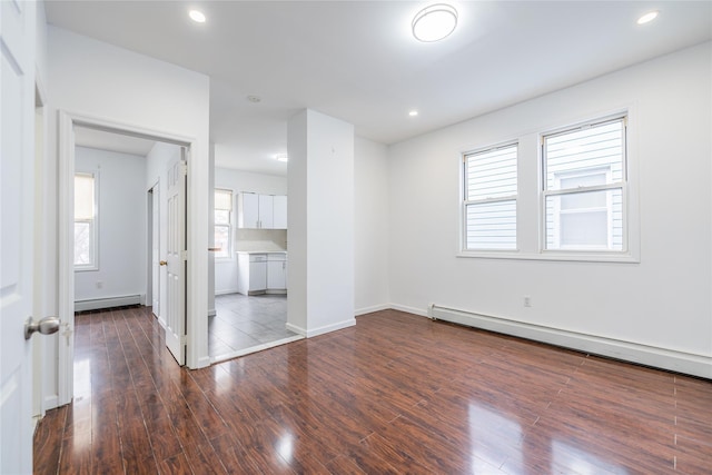 empty room featuring a baseboard radiator, dark wood finished floors, and recessed lighting