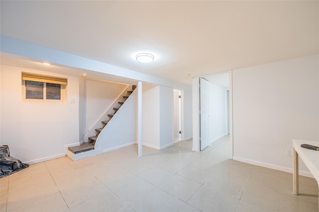 finished below grade area with light tile patterned floors, baseboards, and stairs