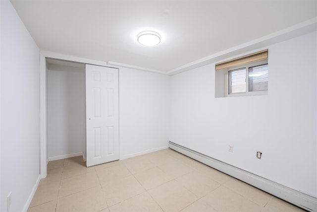 unfurnished bedroom featuring light tile patterned floors, a baseboard radiator, baseboards, and a closet