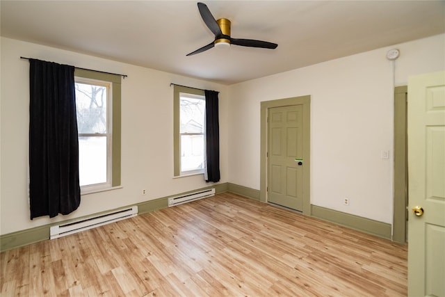 unfurnished room featuring a baseboard heating unit, light wood-style floors, baseboards, and ceiling fan