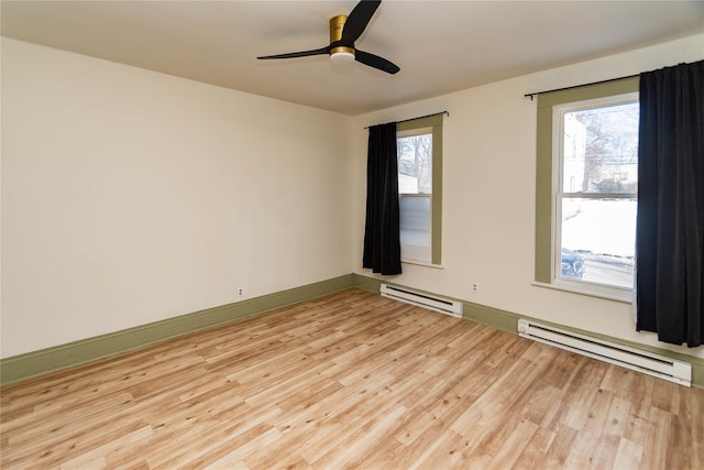 spare room featuring a healthy amount of sunlight, a baseboard radiator, and light wood-style floors