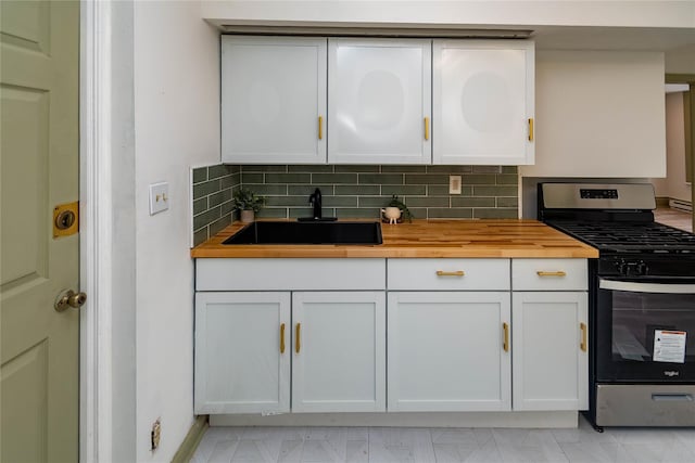 kitchen with backsplash, a sink, stainless steel range with gas stovetop, and white cabinets