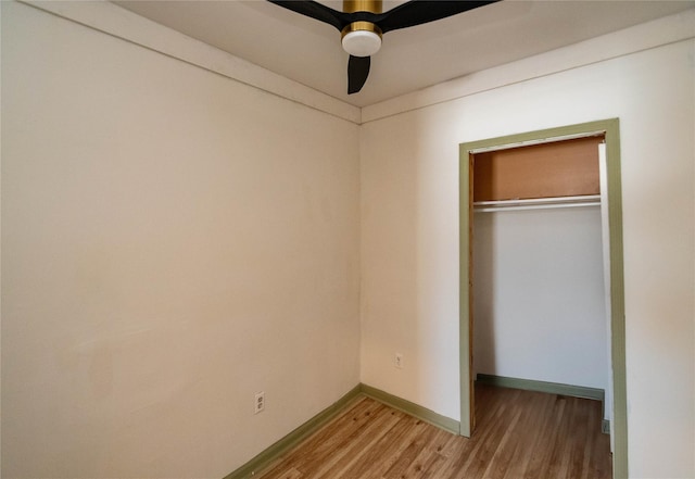 unfurnished bedroom with a closet, wood finished floors, a ceiling fan, and baseboards