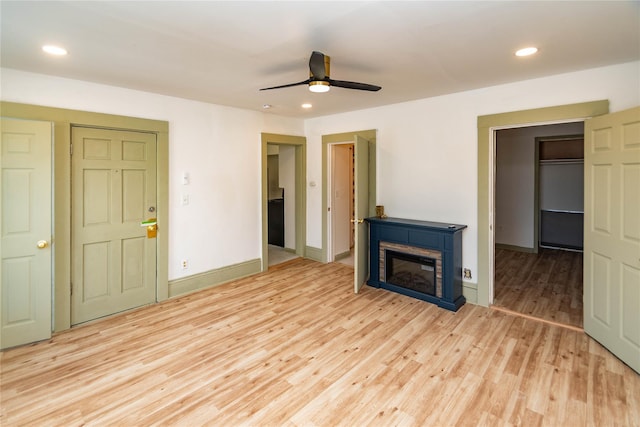 unfurnished living room with light wood-type flooring, recessed lighting, baseboards, and a glass covered fireplace