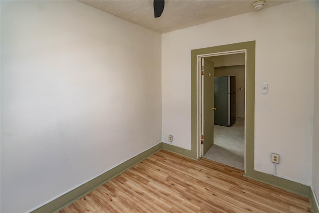 unfurnished room featuring ceiling fan, light wood-type flooring, and baseboards