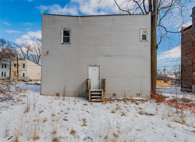 snow covered rear of property featuring entry steps, crawl space, and a garage