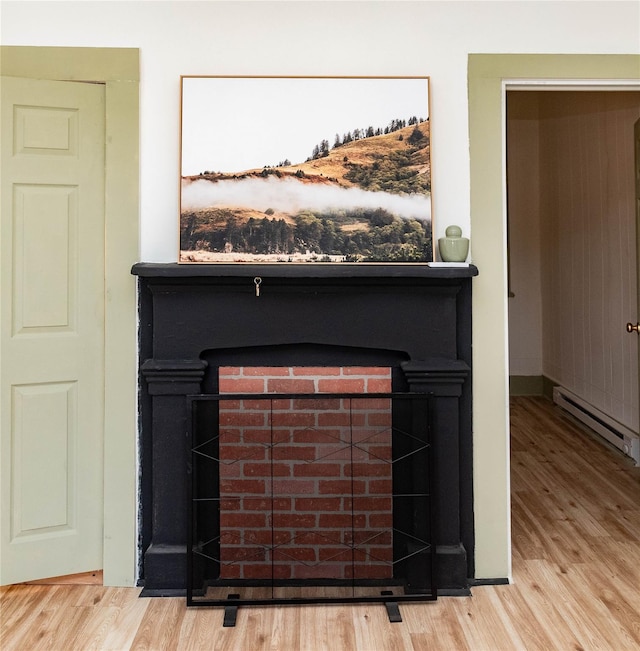 room details with a baseboard heating unit, a fireplace, and wood finished floors