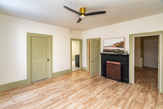 unfurnished living room featuring ceiling fan, a fireplace, light wood-style flooring, and baseboards