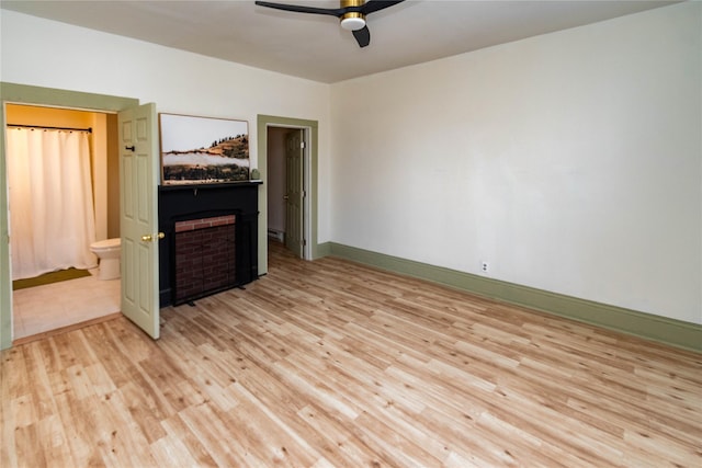 unfurnished bedroom featuring light wood-type flooring, a fireplace, baseboards, and a ceiling fan