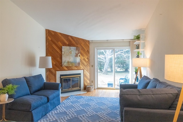 living room with a fireplace, wood finished floors, and wooden walls