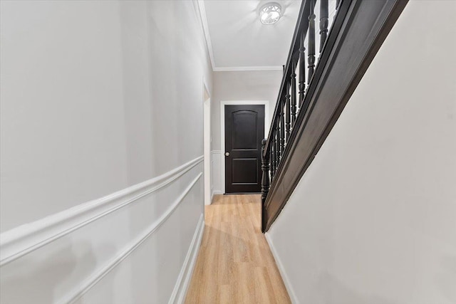 hallway with stairs, ornamental molding, and light wood-style flooring