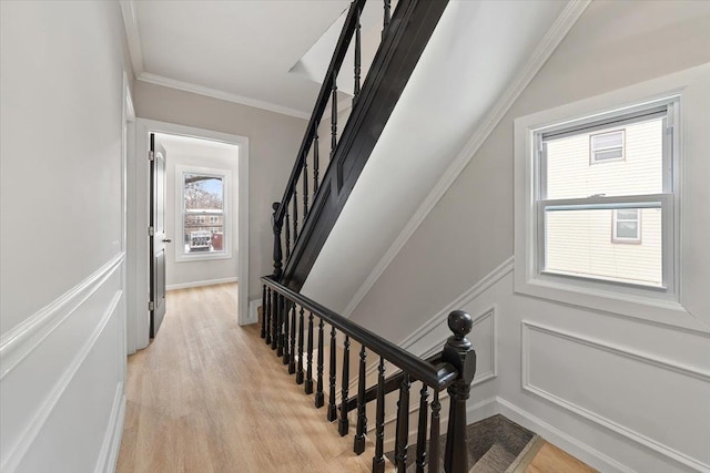 stairway featuring a decorative wall, wood finished floors, and crown molding