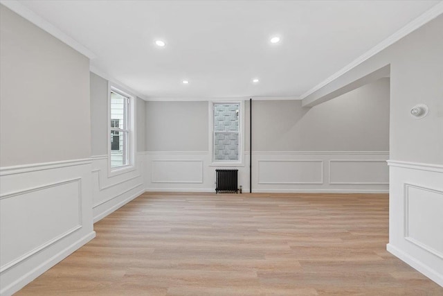 spare room featuring light wood-style floors, recessed lighting, radiator, and crown molding