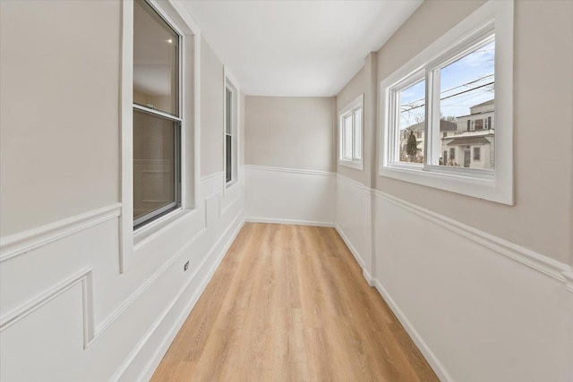 corridor with light wood-style floors and baseboards