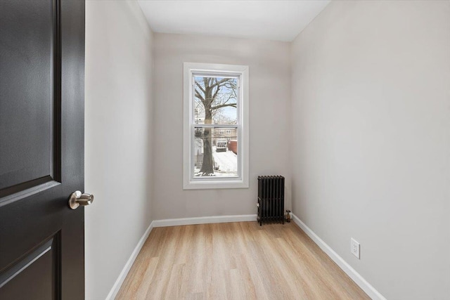 empty room with radiator, light wood finished floors, and baseboards