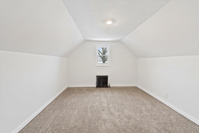 additional living space featuring vaulted ceiling, radiator heating unit, carpet, and baseboards