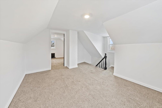 bonus room with light carpet, vaulted ceiling, and baseboards