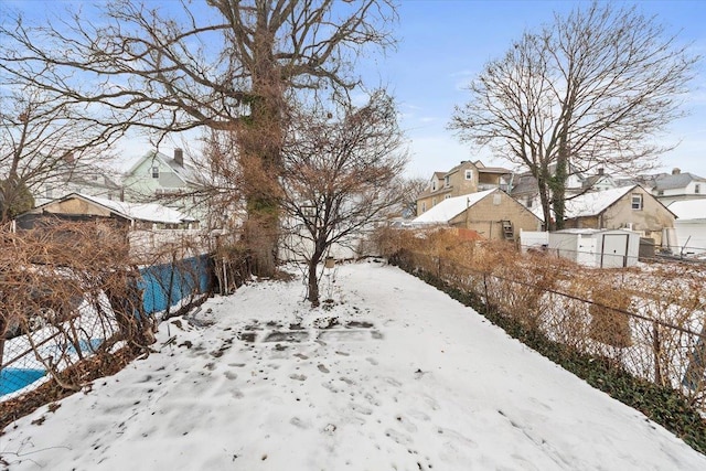 yard covered in snow featuring a residential view and fence