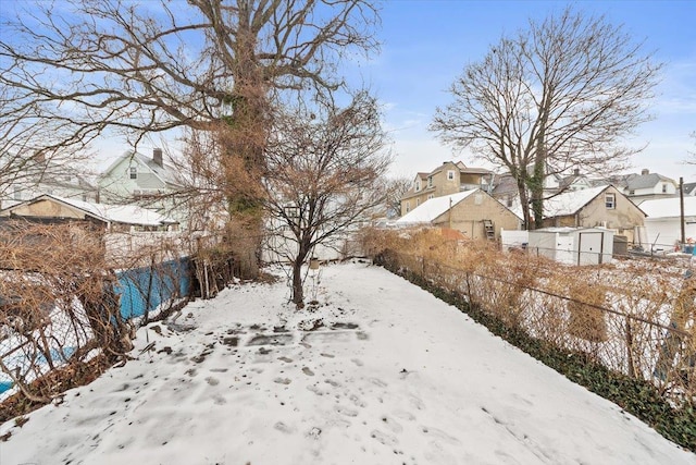 yard layered in snow with a residential view and fence