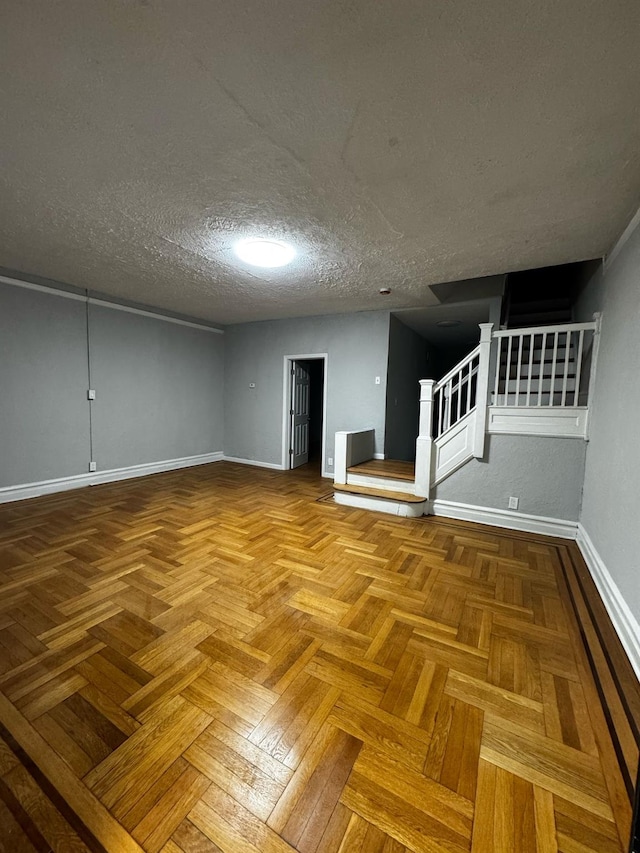 unfurnished room featuring stairs, a textured ceiling, and baseboards