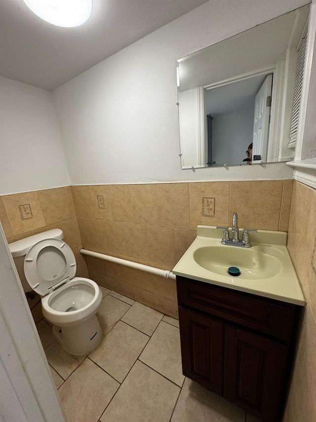 bathroom with tile patterned flooring, toilet, tile walls, and vanity