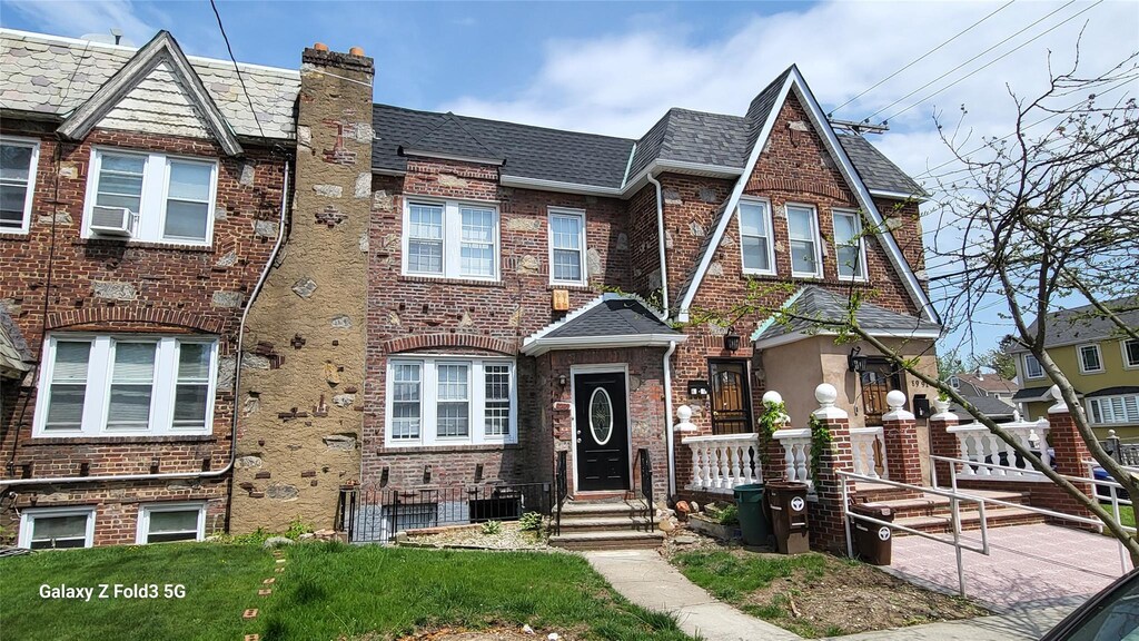 8989 Vanderveer St, Jamaica, NY 11427 - view of property with brick siding, a shingled roof, cooling unit, and a chimney